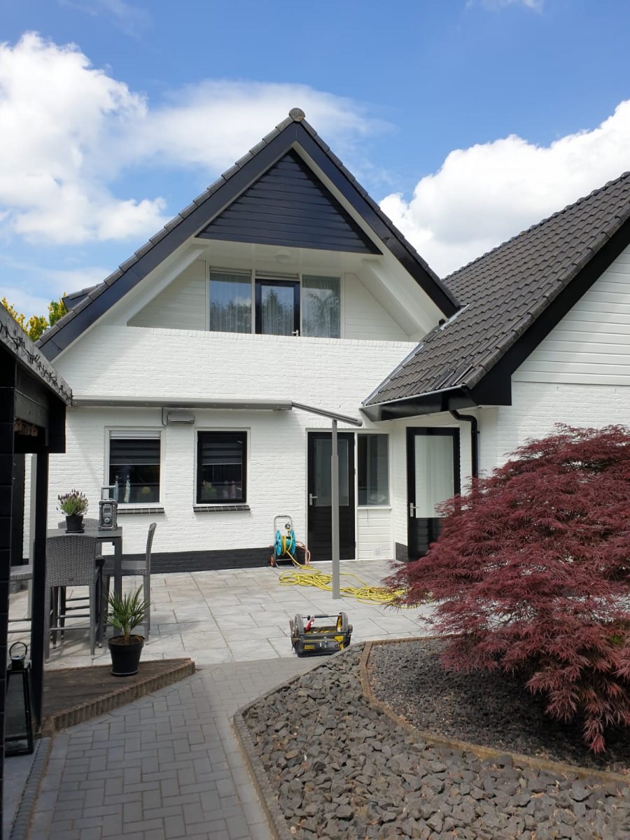 Witte woning met donkere dakpannen en kozijnen